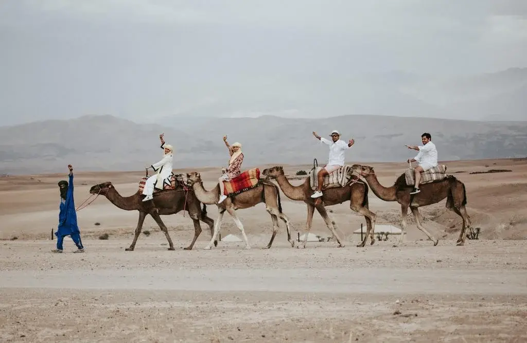 A group on a camel ride in the Agafay Desert under a cloudy sky